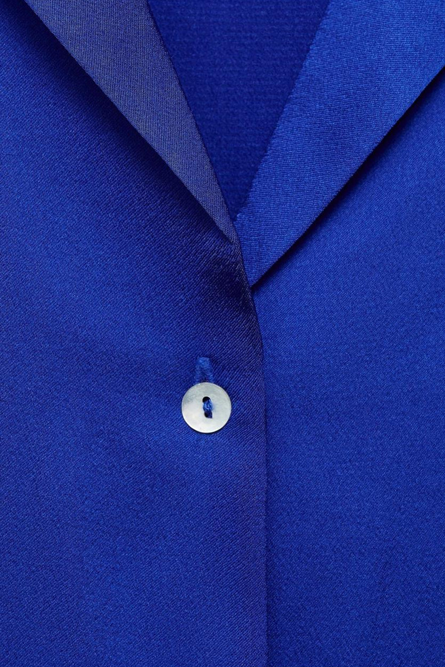 Blauwe blouse met korte mouwen van MANGO, met een witte knoop en satijnen afwerkingen.