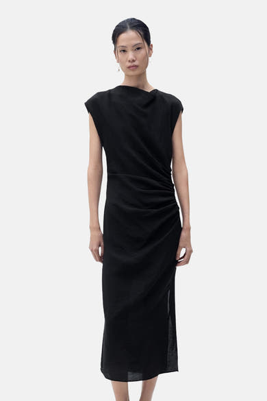 Zwarte MANGO jurk met gedrapeerde halslijn en subtiele textuur gedragen door een model.