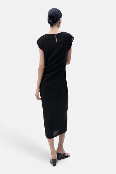 Zwarte jurk van MANGO, met druppelvormige sluiting aan de achterkant en lange asymmetrische zoom.