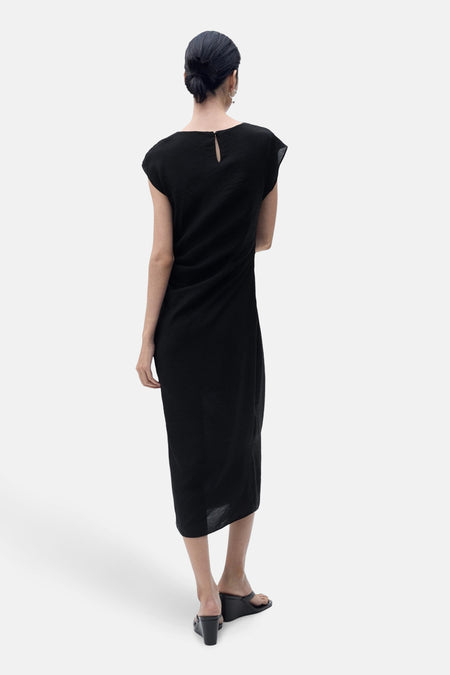 Zwarte jurk van MANGO, met druppelvormige sluiting aan de achterkant en lange asymmetrische zoom.
