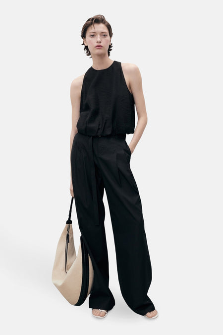 Zwart mouwloos overhemd van MANGO, gedragen met een wijde broek en een beige tas.