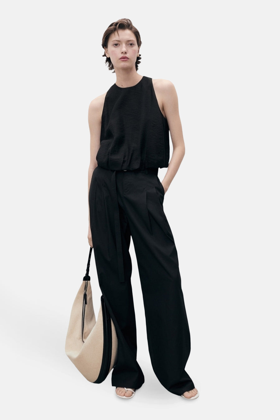 Zwart mouwloos overhemd van MANGO, gedragen met een wijde broek en een beige tas.