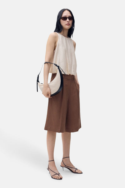 Beige mouwloos overhemd van MANGO, gedragen met een bruine korte broek en een schoudertas.