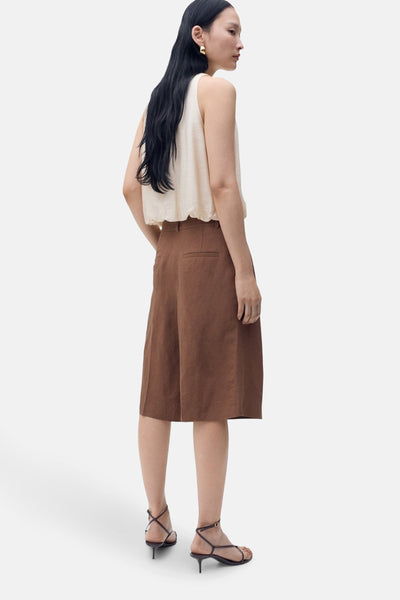 Beige mouwloos overhemd van MANGO, gedragen met een bruine rok en sandalen met hak.