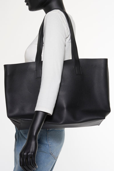 Grand sac à bandoulière noir de MANGO, porté sur l'épaule par un mannequin en jean et t-shirt blanc.