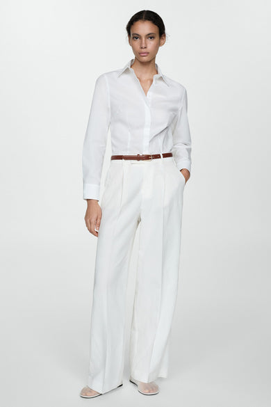 Wit overhemd met lange mouwen van MANGO, gedragen met een witte broek met hoge taille en een bruine riem.