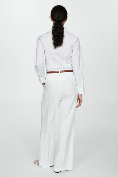 Wit overhemd met lange mouwen van MANGO, gedragen met een bruine riem en een witte broek met hoge taille.