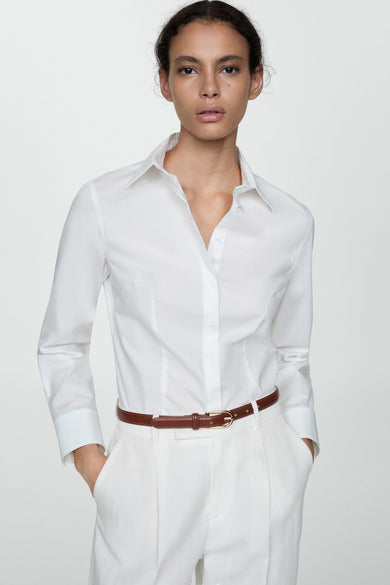 Wit overhemd met lange mouwen van MANGO, gedragen met een bruine riem en een witte broek.