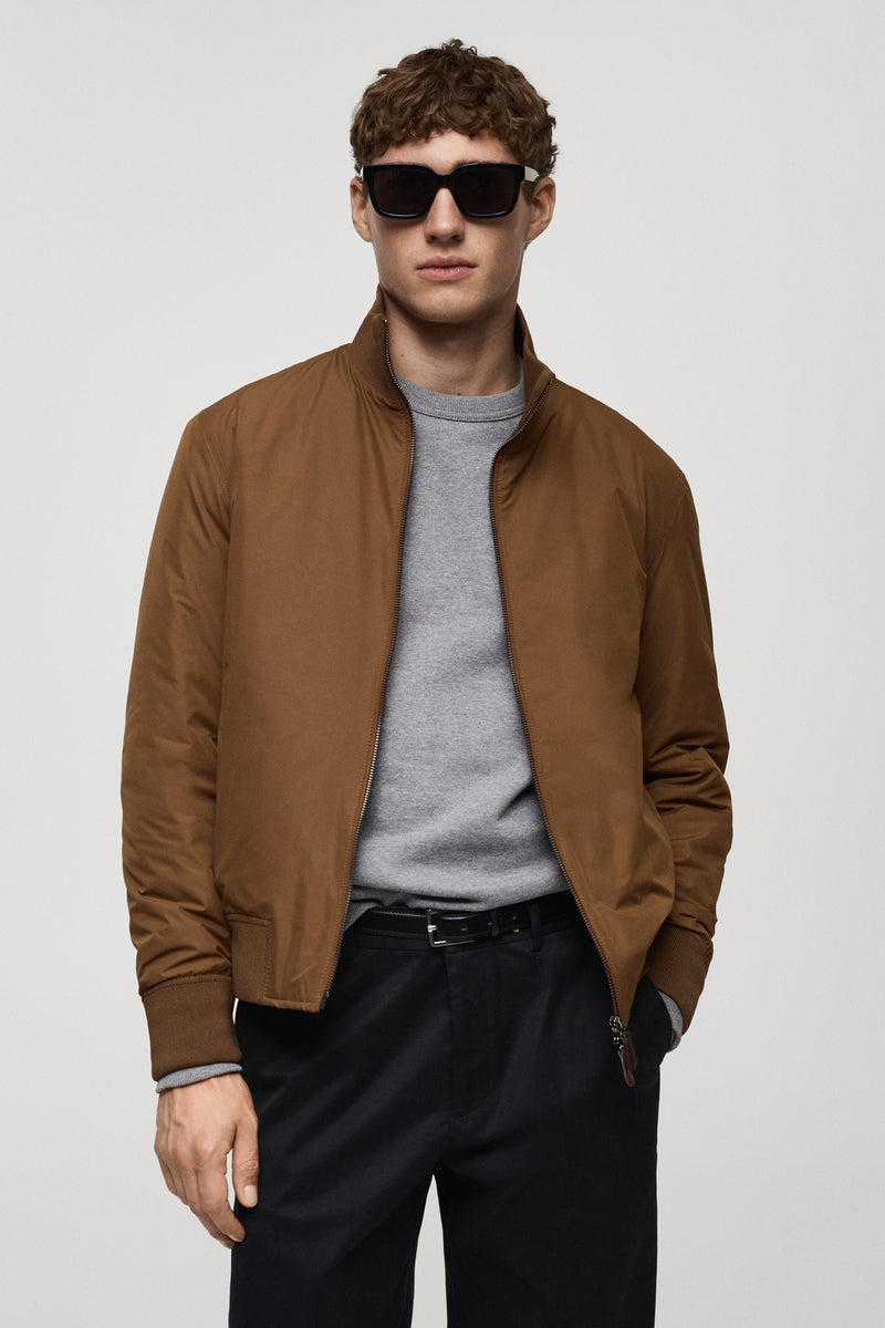 Kort bruin jasje van MANGO, van achteren gezien, met geribde kraag en zoom, gedragen met een zwarte broek.