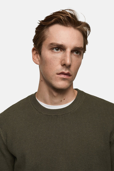 Kaki ronde hals trui van MANGO, in ribgebreide stof, gedragen over een wit T-shirt.