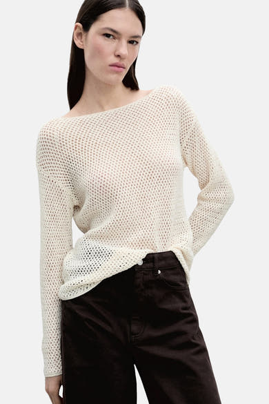 Pull à col rond écru de MANGO porté avec un pantalon marron uni.