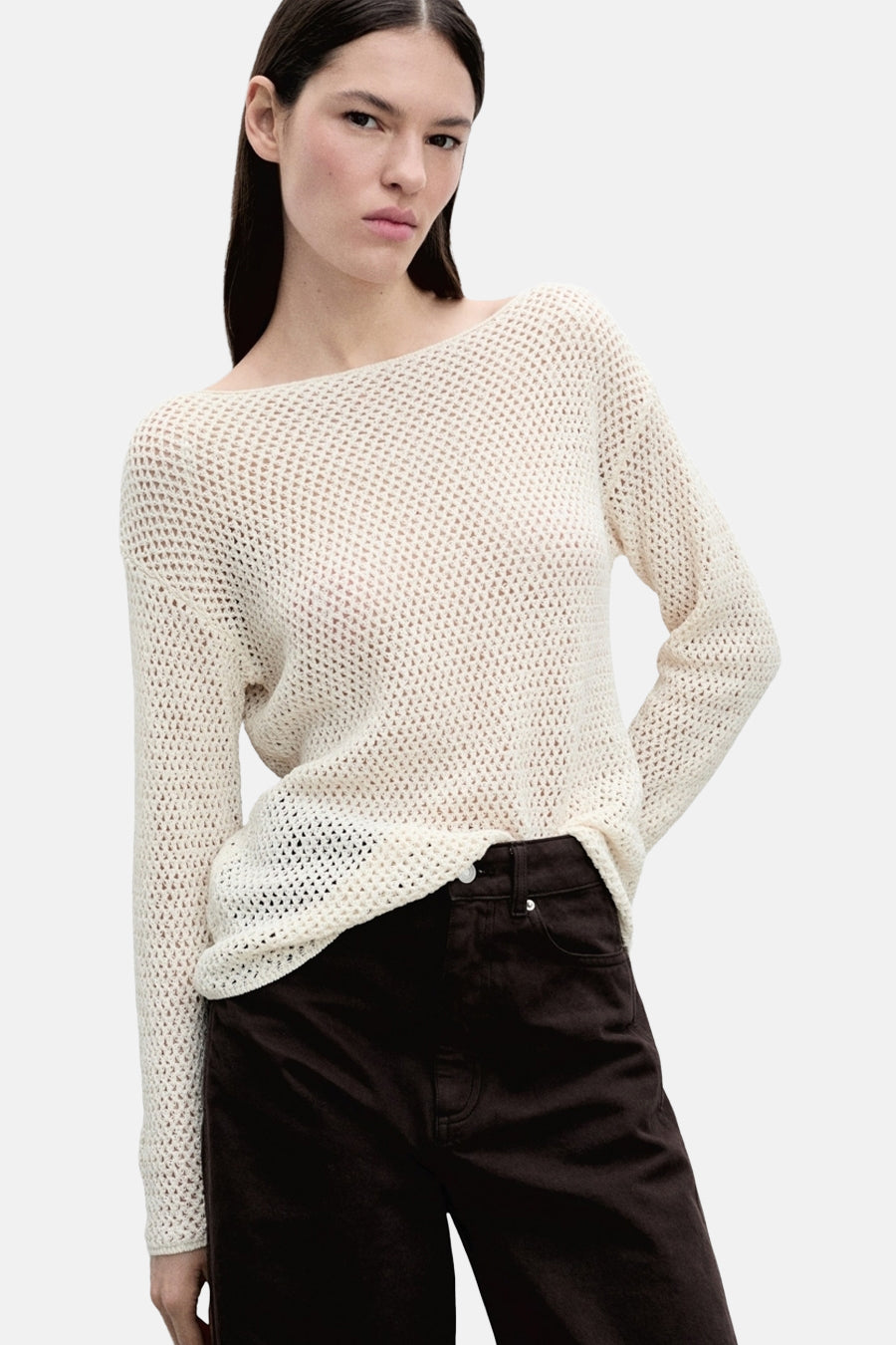 Pull à col rond écru de MANGO porté avec un pantalon marron uni.