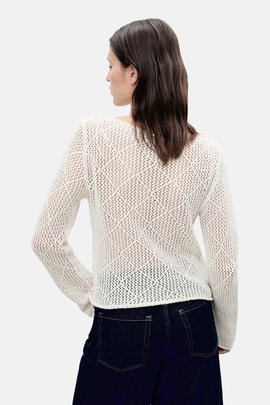 Pull à col rond écru de MANGO, en maille ajourée, porté avec un pantalon en jean sombre, vue de dos.
