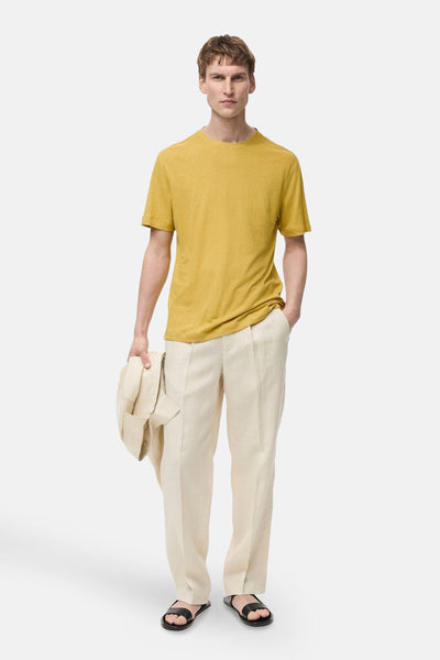 T-shirt à manches courtes jaune de MANGO, porté avec un pantalon en lin beige et des sandales.