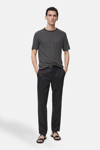 T-shirt noir à rayures horizontales by MANGO, porté avec un pantalon noir et des sandales en cuir.