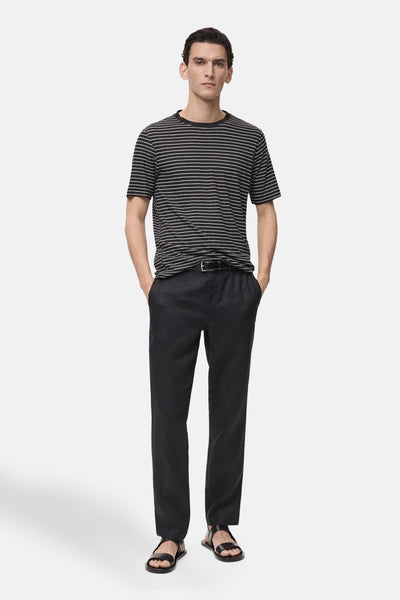 T-shirt noir à rayures horizontales by MANGO, porté avec un pantalon noir et des sandales en cuir.