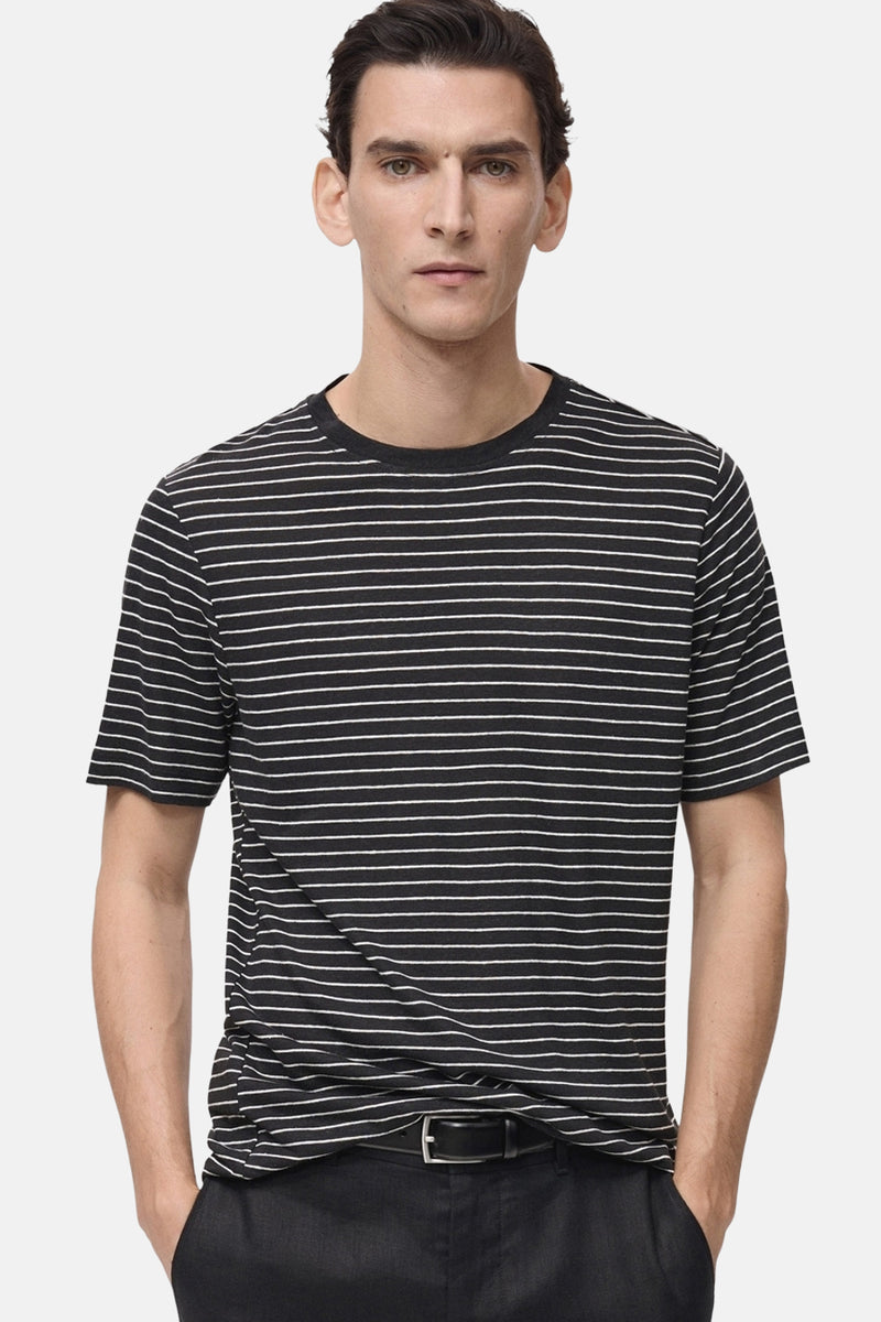 T-shirt noir à rayures blanches de MANGO, porté avec un pantalon noir.