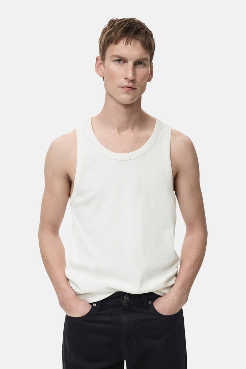 Witte tanktop van MANGO, gedragen met een zwarte jeans, model poseert met handen in de zakken.