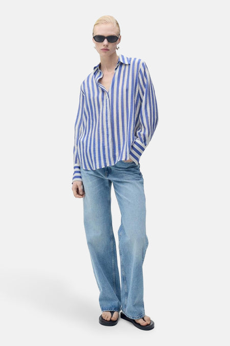 Blauw gestreept overhemd met lange mouwen van MANGO, gedragen met een wijde jeans en zwarte sandalen.