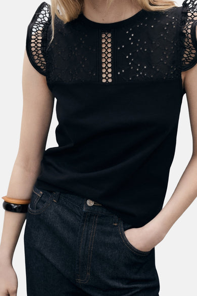 Top noir sans manches de MANGO, avec empiècement en dentelle ajourée sur le haut et porté avec un jean foncé.
