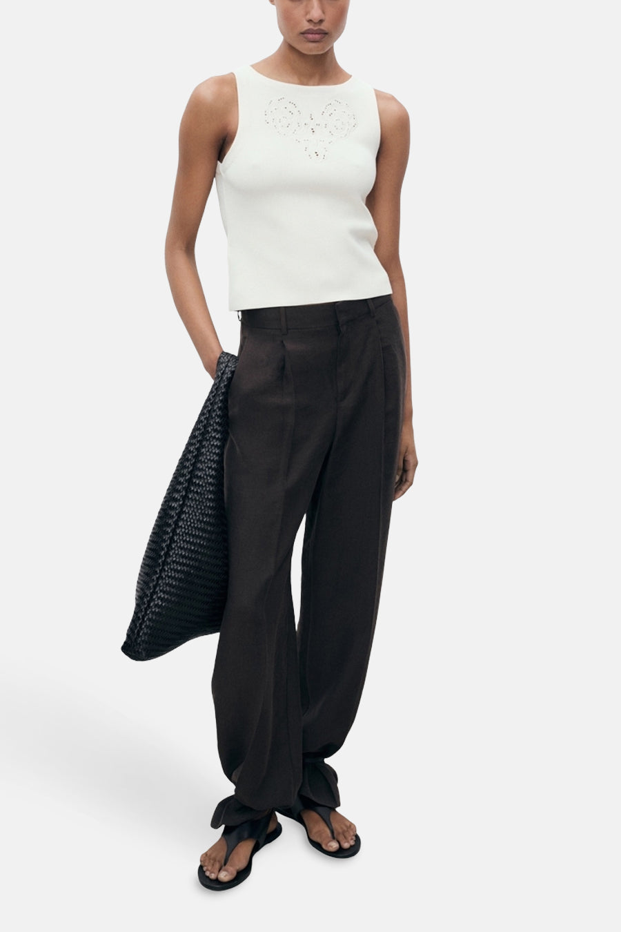 Ecru hemdje van MANGO, met decoratieve ajourdetails, gedragen met een donkere broek en zwarte sandalen.