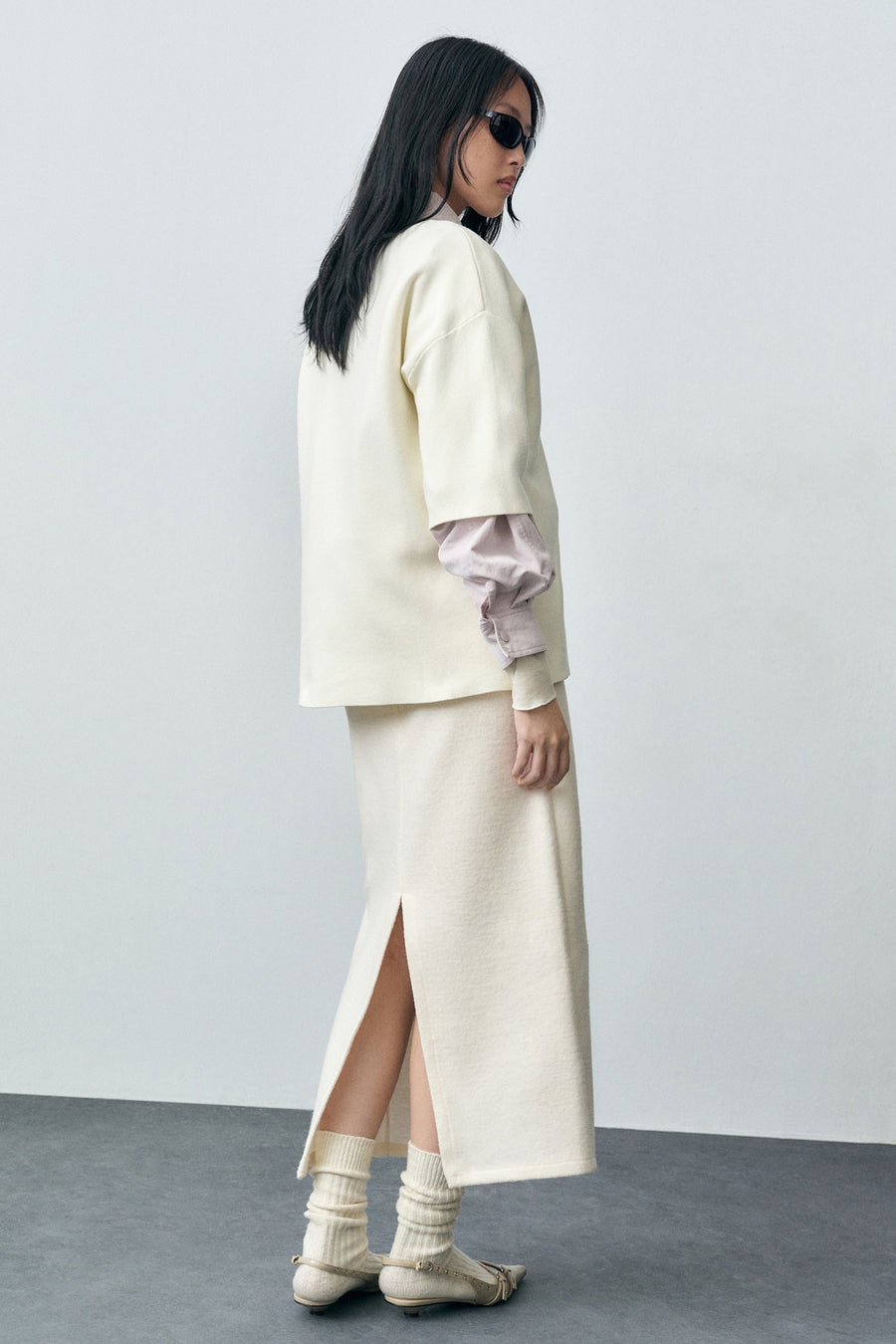 Ecru ronde hals trui van MANGO, gedragen met een midi rok met split, hoge sokken en ballerina's met studs.