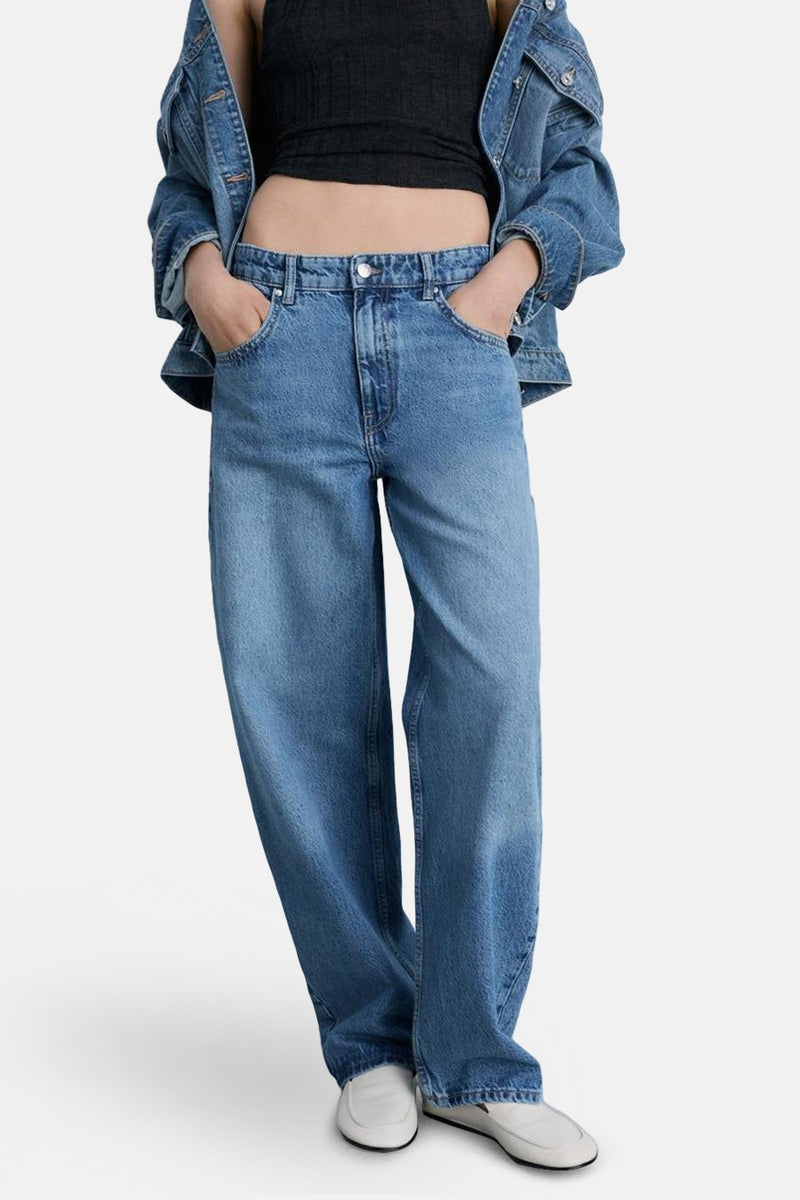 Wijde spijkerbroek in middieblauw denim van MANGO, gedragen met een zwarte top en een spijkerjasje.