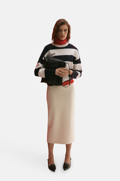 Blauwe gestreepte trui met ronde hals van MANGO, gedragen met een rode coltrui, een beige rok en zwarte schoenen.