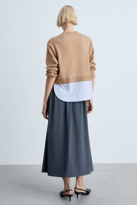 Pull à col rond marron de MANGO, porté avec une chemise blanche et une jupe longue foncée, vue de dos.
