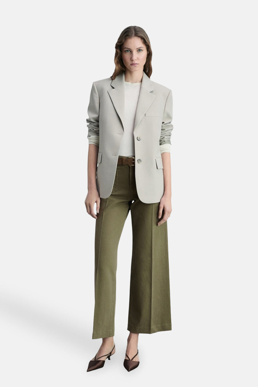 Kaki kleurige broek van MANGO, gedragen met een bruine riem, een gebroken wit T-shirt en een lichtgrijs blazer.