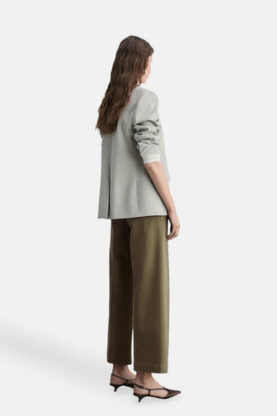 Kaki broek van MANGO, wijde pasvorm, gedragen met een grijze blazer en muiltjes.