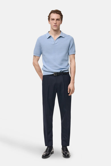 Polo à manches courtes bleu de MANGO, texture côtelée, porté avec un pantalon de ville et des mocassins noirs.