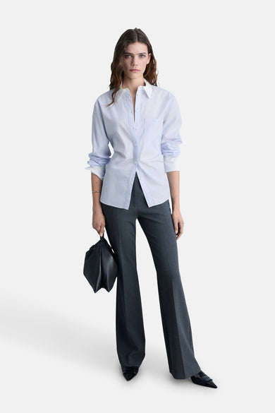 Blauw overhemd met lange mouwen van MANGO, gedragen met een grijze broek en een zwarte tas.