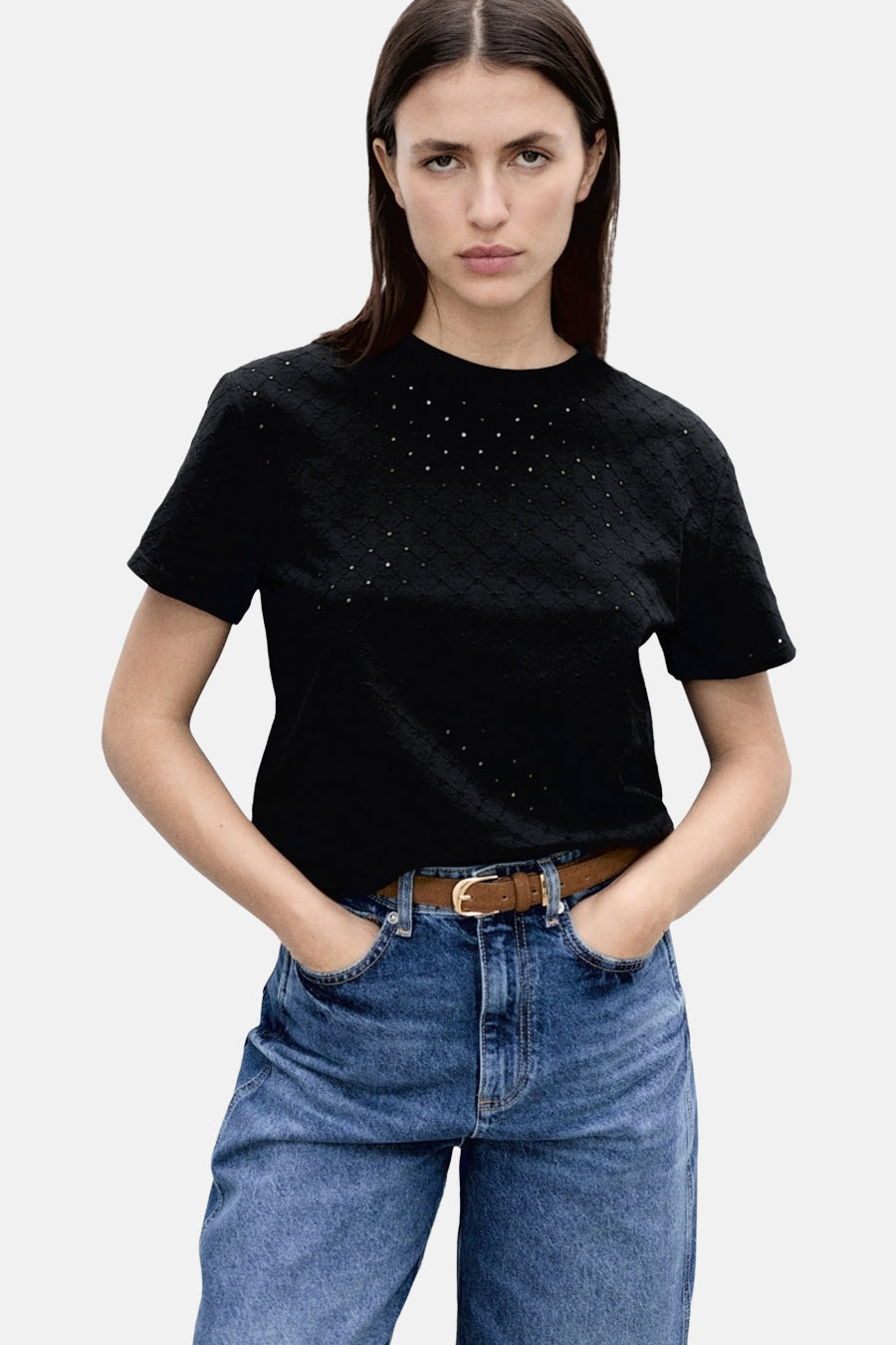 T-shirt noir à manches courtes de MANGO, orné de petits détails brillants et porté avec un jean taille haute.
