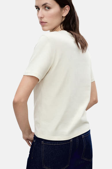T-shirt beige à manches courtes de MANGO, vu de dos, porté avec un jean bleu foncé.
