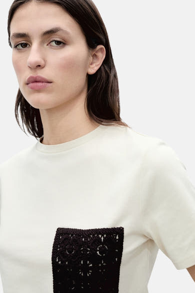 T-shirt beige à manches courtes de MANGO, orné d'une poche carrée en crochet noire.
