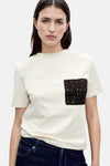 T-shirt beige à manches courtes de MANGO, avec poche crochetée marron sur le devant.