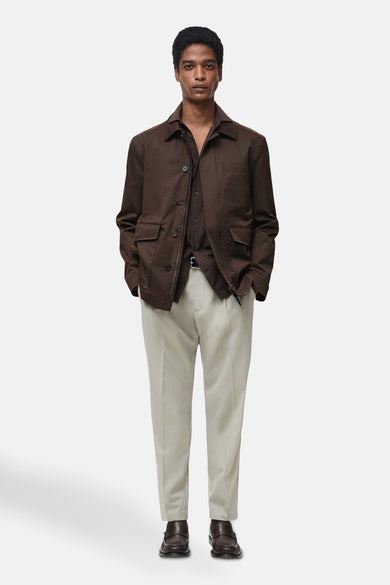 Kort bruin jasje van MANGO, met opgestikte zakken en gedragen over een licht overhemd en een lichte broek.