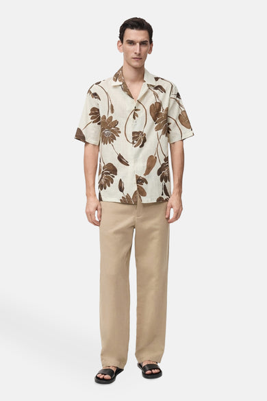 Bruin overhemd met korte mouwen van MANGO met bloemenprint, gedragen met een beige broek en sandalen.
