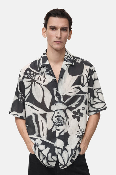 Chemise à manches courtes multicolore de MANGO, à motif floral noir et blanc, avec un col ouvert.