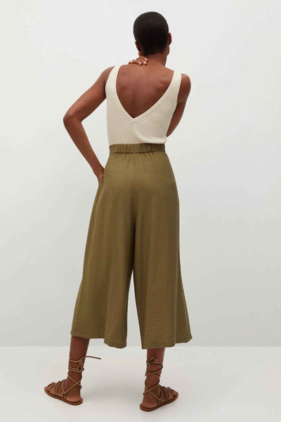 Pantalon olive coupe ample, de MANGO, porté avec un débardeur en maille et des sandales lacées.