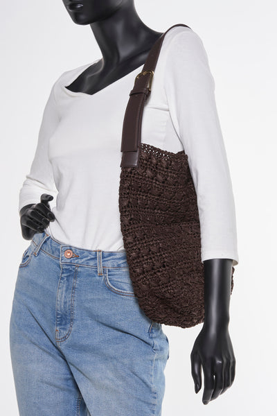 Sac à bandoulière marron tressé par MANGO, porté avec un jean bleu et un t-shirt blanc à manches longues.