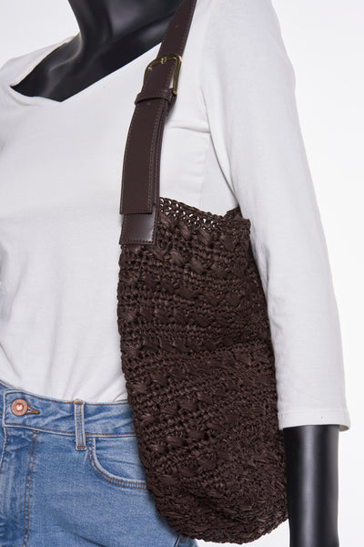 Sac à bandoulière brun en raphia de MANGO, porté à l'épaule avec un t-shirt blanc et un jean.
