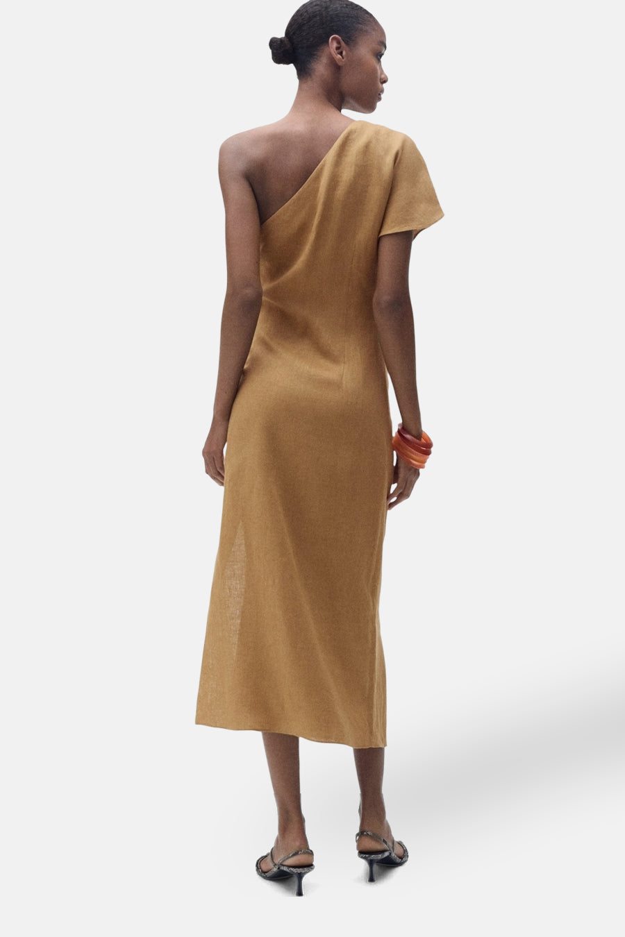 Bruine jurk van MANGO, asymmetrische snit, midi-lengte, gedragen met sandalen met hakken en een oranje armband.