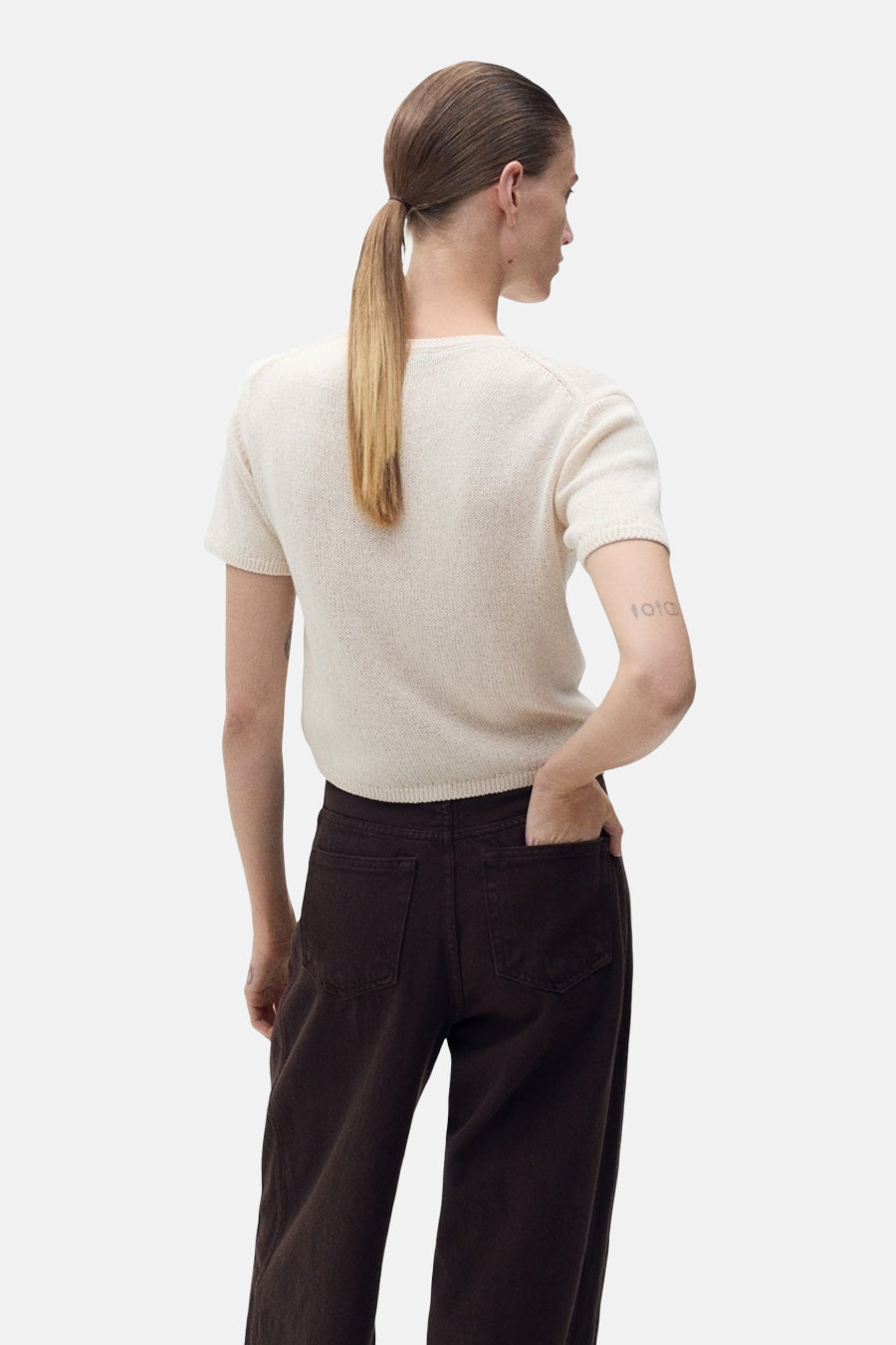 Pull à col rond beige de MANGO, porté avec un pantalon marron, vue de dos.