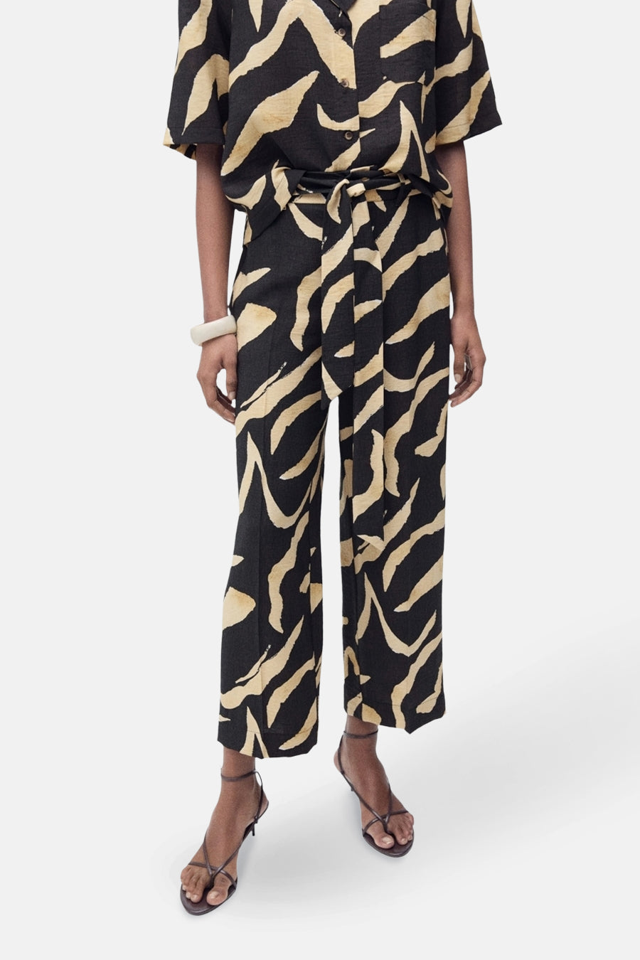 Zwarte broek met golvend patroon van MANGO, gedragen met bijpassende riem en hoge hakken.