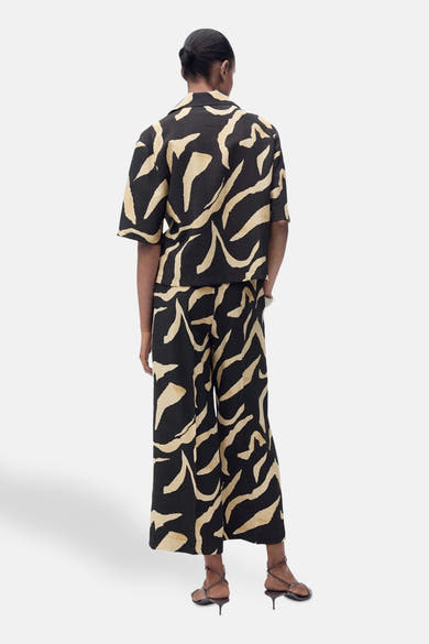 Zwarte broek met golvend patroon, van MANGO, gedragen met een bijpassend overhemd en sandalen met dunne hak.