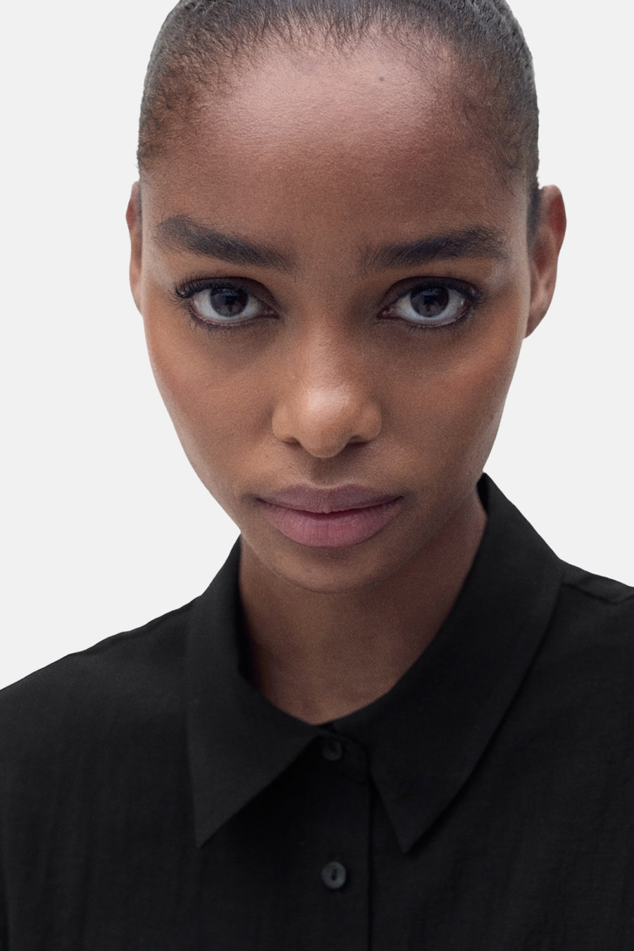 Zwarte blouse met korte mouwen van MANGO, gedragen met een klassieke geknoopte kraag en een elegante pasvorm.