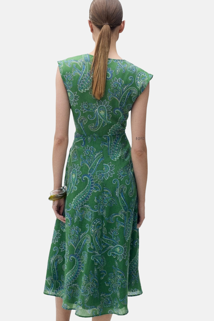 Groene jurk van MANGO, met blauw paisley-patroon, gedragen met een transparante armband, van achteren gezien.
