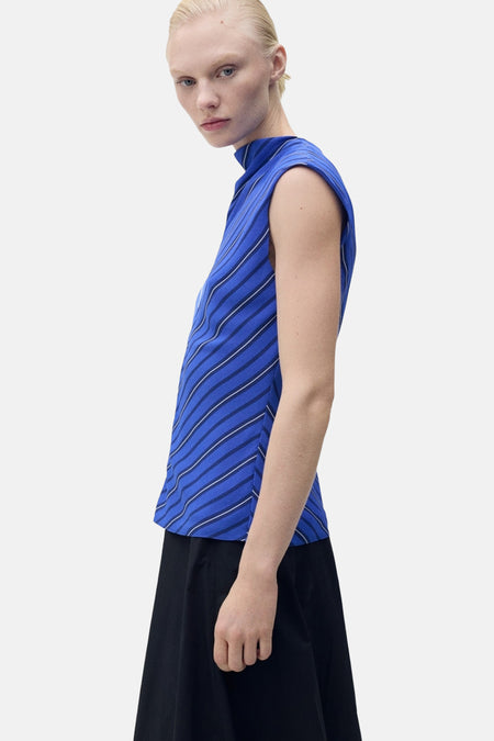 Mouwloos blauw overhemd van MANGO, diagonale witte strepen, gedragen met een wijde zwarte rok.